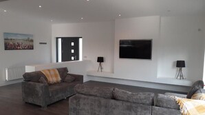A spacious living room with two grey sofas, a large flat-screen TV, and a painting on the wall. - Stable Hill House,
5km from Killarney Town
Private & Peaceful Location
 (Killarney)