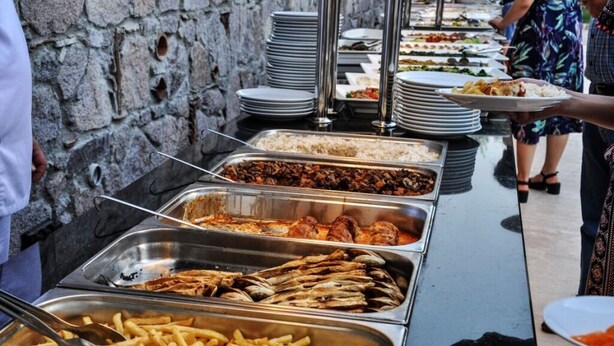 Un bufé con diversas opciones de comida, incluyendo carnes, pescado y papas fritas.