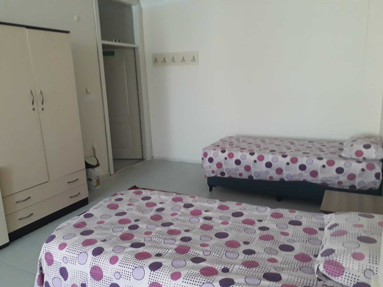 A bedroom with two single beds, a wardrobe, and a door leading to another room.