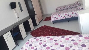 Un dormitorio con dos camas, un escritorio, un armario y un televisor.