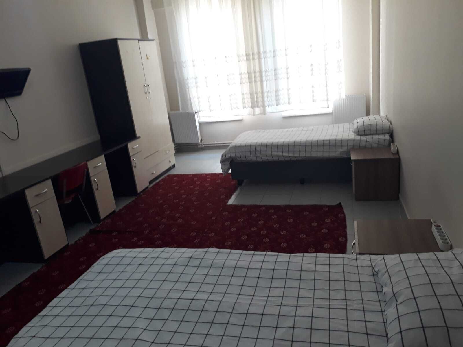A room with two beds, a desk, and a wardrobe.
