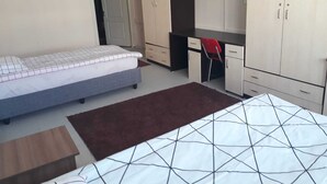 Un dormitorio con dos camas, un escritorio, una silla y un televisor.