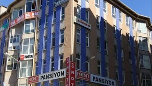 Un edificio de varios pisos con señalización comercial, incluyendo 'Pansiyon' y 'Sivas Kelle & Corbacisi'.