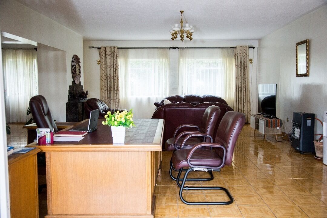 Una sala de estar con un escritorio de madera, sillones de cuero, un sofá, una araña y una televisión.