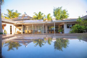 Una casa con piscina, paneles solares y un patio cubierto.