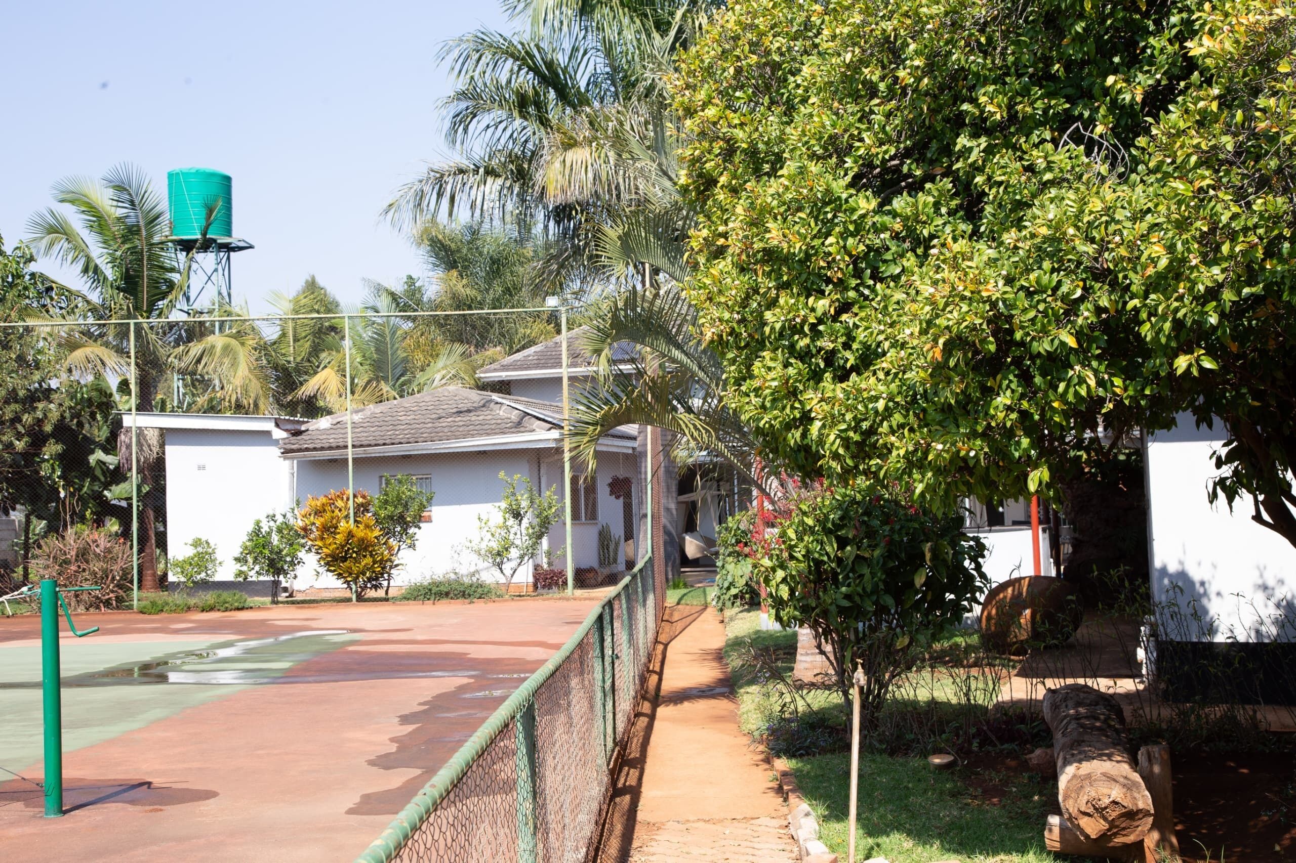 A residential area with a fenced playground, a water tank, and a house with a sloped roof.