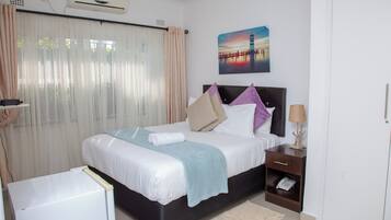 A neatly arranged hotel room with a bed, bedside table, lamp, and a painting on the wall.