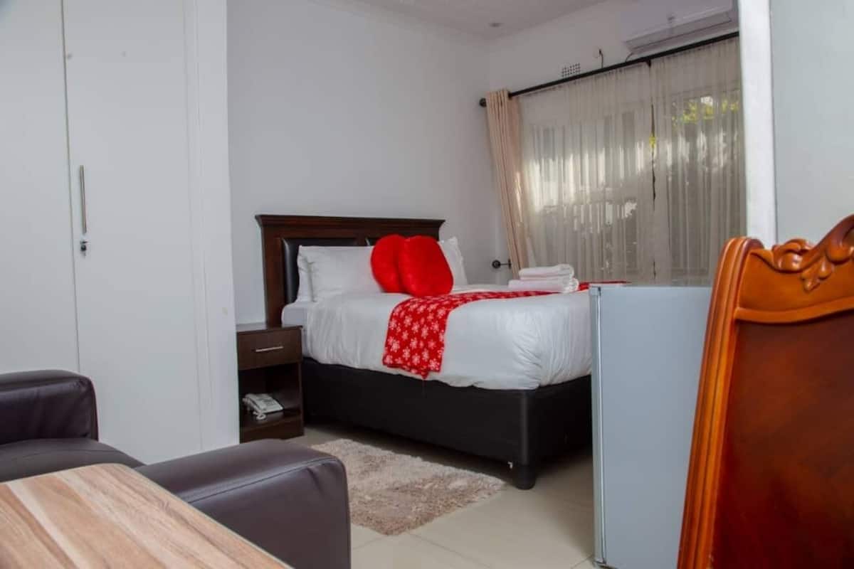 A hotel room with a bed, a desk, a chair, and a wardrobe.
