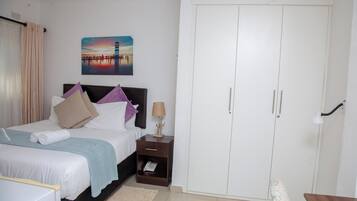 A bedroom with a bed, nightstand, wardrobe, and a painting on the wall.