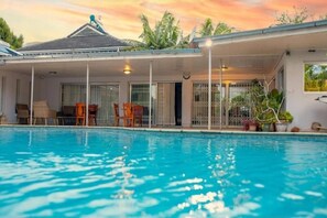 Relax by the pool surrounded by lush greenery and comfortable seating.