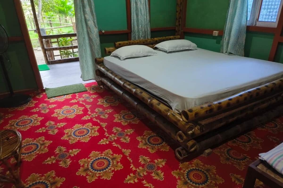 A room with a bed, a fan, and a red patterned carpet.