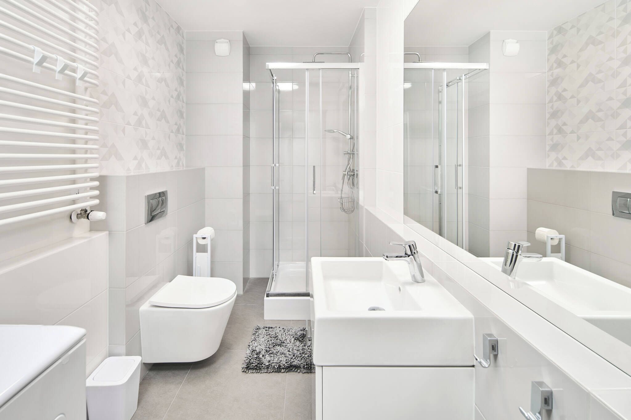 A modern bathroom with a glass-enclosed shower, a white toilet, and a large mirror.