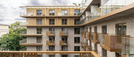 A multi-story building with balconies, large windows, and a brick facade.