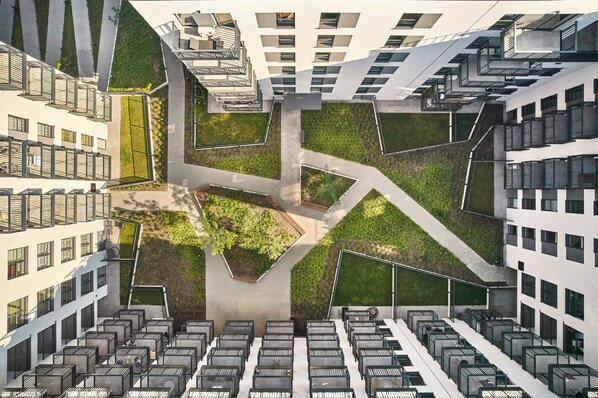 A high-rise residential building with multiple balconies, a central courtyard with greenery, and a modern architectural design. - Symphony Atal City Square (Wroclaw)