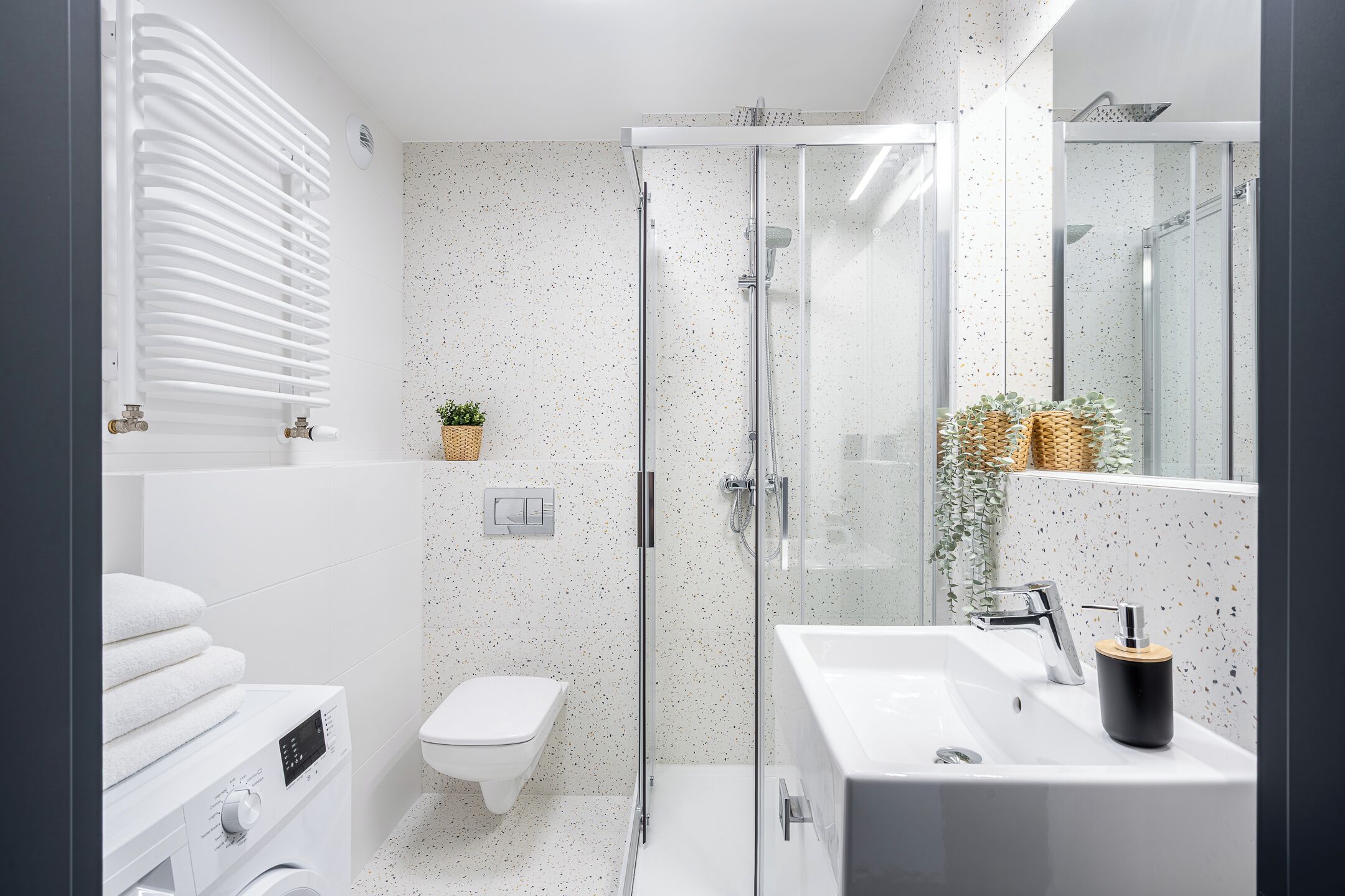 Een moderne badkamer met een douchecabine van glas, een wit wastafelmeubel en een toilet.