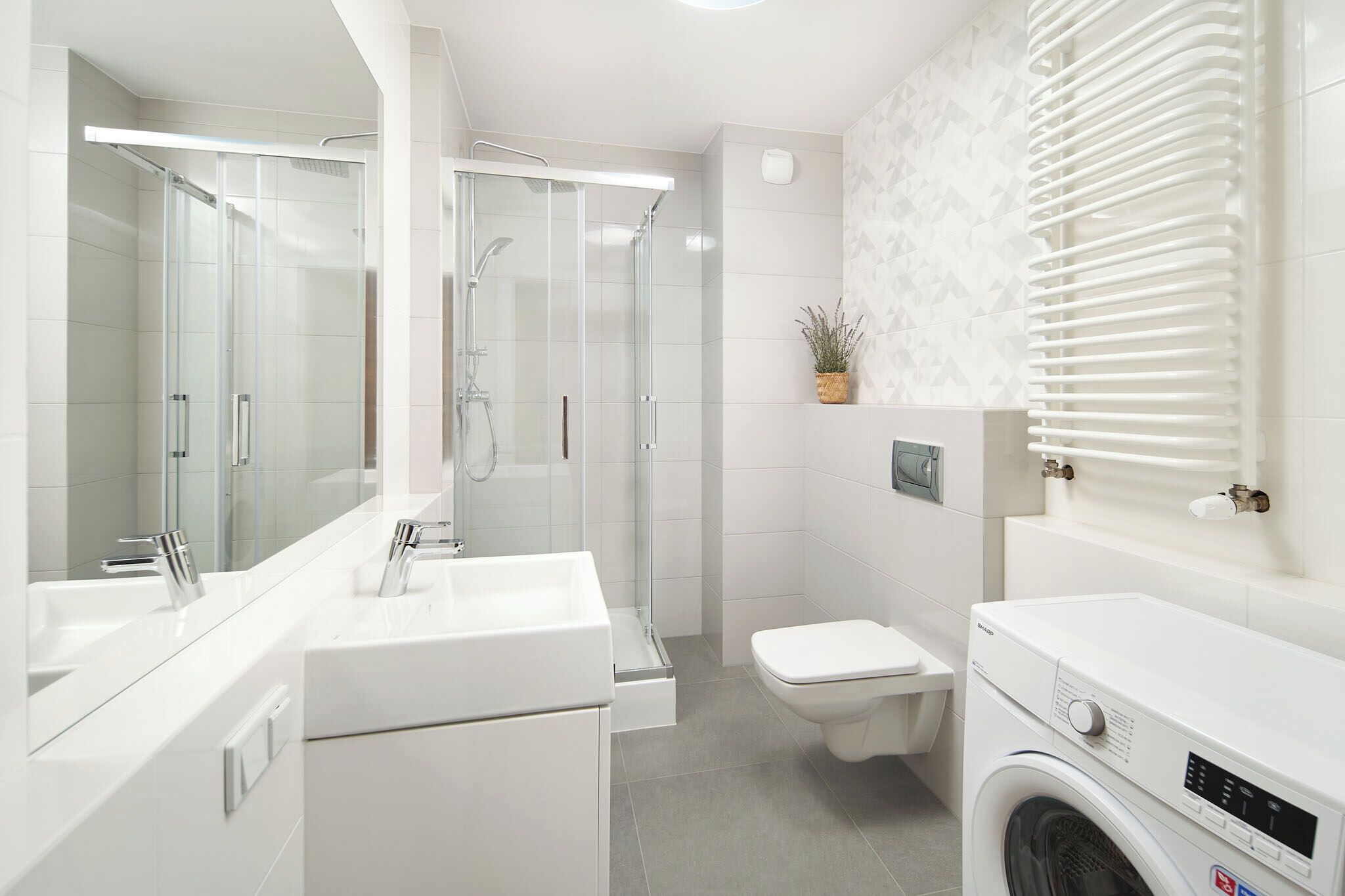 Un baño moderno con ducha envuelta en vidrio, inodoro y lavadora.