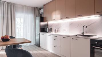 Una cocina moderna con armarios blancos, encimera de mármol y horno empotrado.
