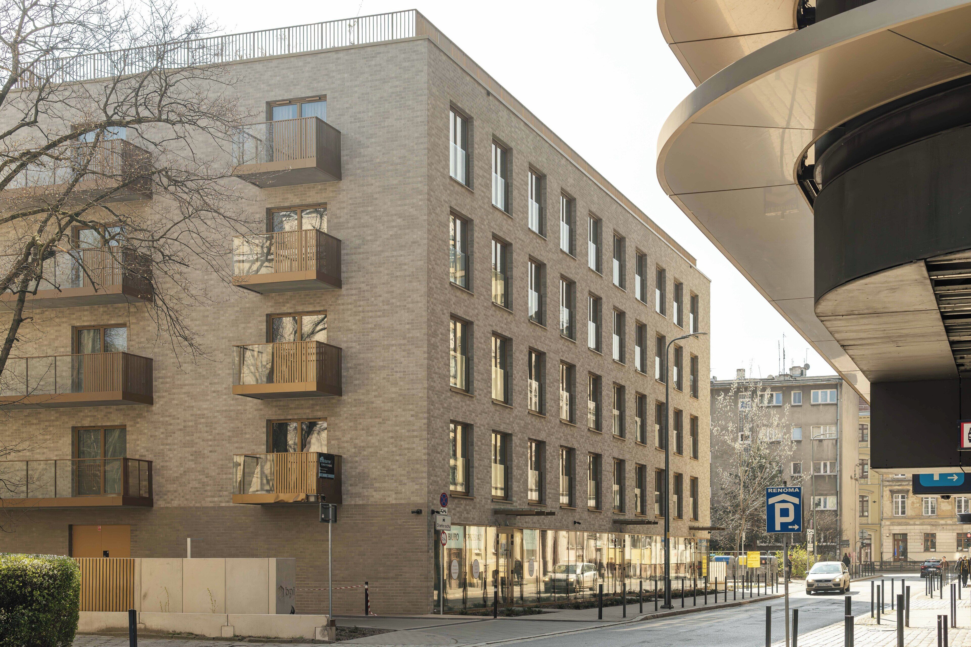 A multi-story building with balconies and a parking sign.