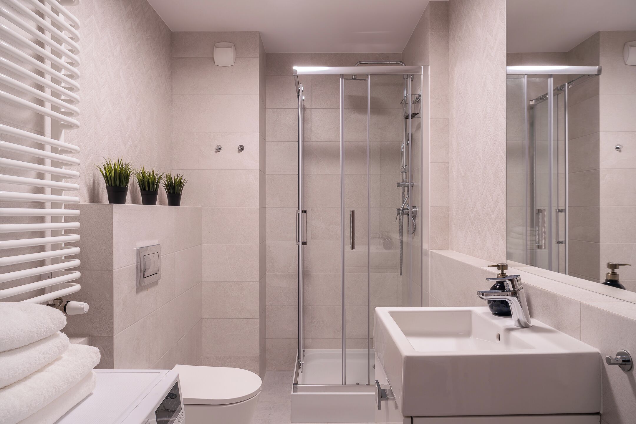 Un baño moderno con cabina de ducha de vidrio, un lavabo blanco y un inodoro.