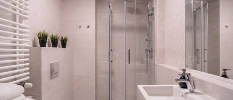 Un baño moderno con cabina de ducha de vidrio, un lavabo blanco y un inodoro.