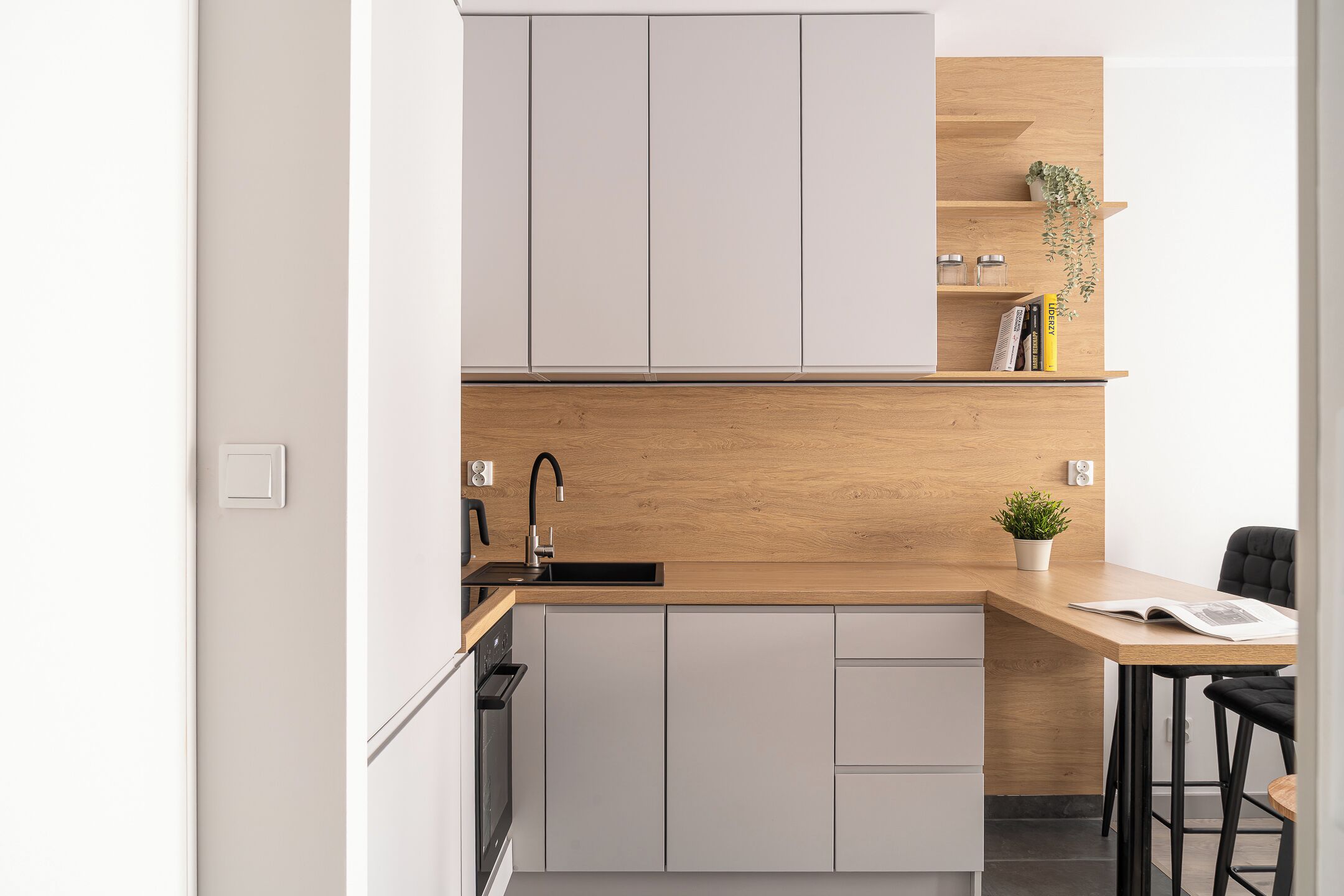 A modern kitchen with white cabinets, a wooden countertop, and a black faucet.