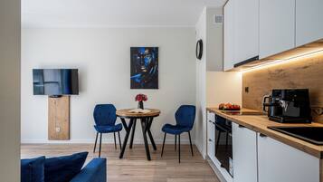 A modern kitchen with a wooden countertop, a coffee machine, and a dining area with two chairs and a table.