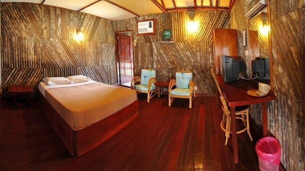 A room with a bed, two chairs, a desk, and a television. - Dragon Inn Floating Resort Semporna (Semporna)