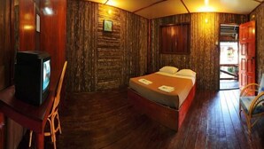 A room with a bed, a television, a wooden wall, and a door. - Dragon Inn Floating Resort Semporna (Semporna)
