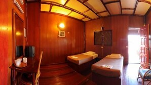 A room with wooden walls and a sloped ceiling, two single beds, a desk with a chair, and a television. - Dragon Inn Floating Resort Semporna (Semporna)