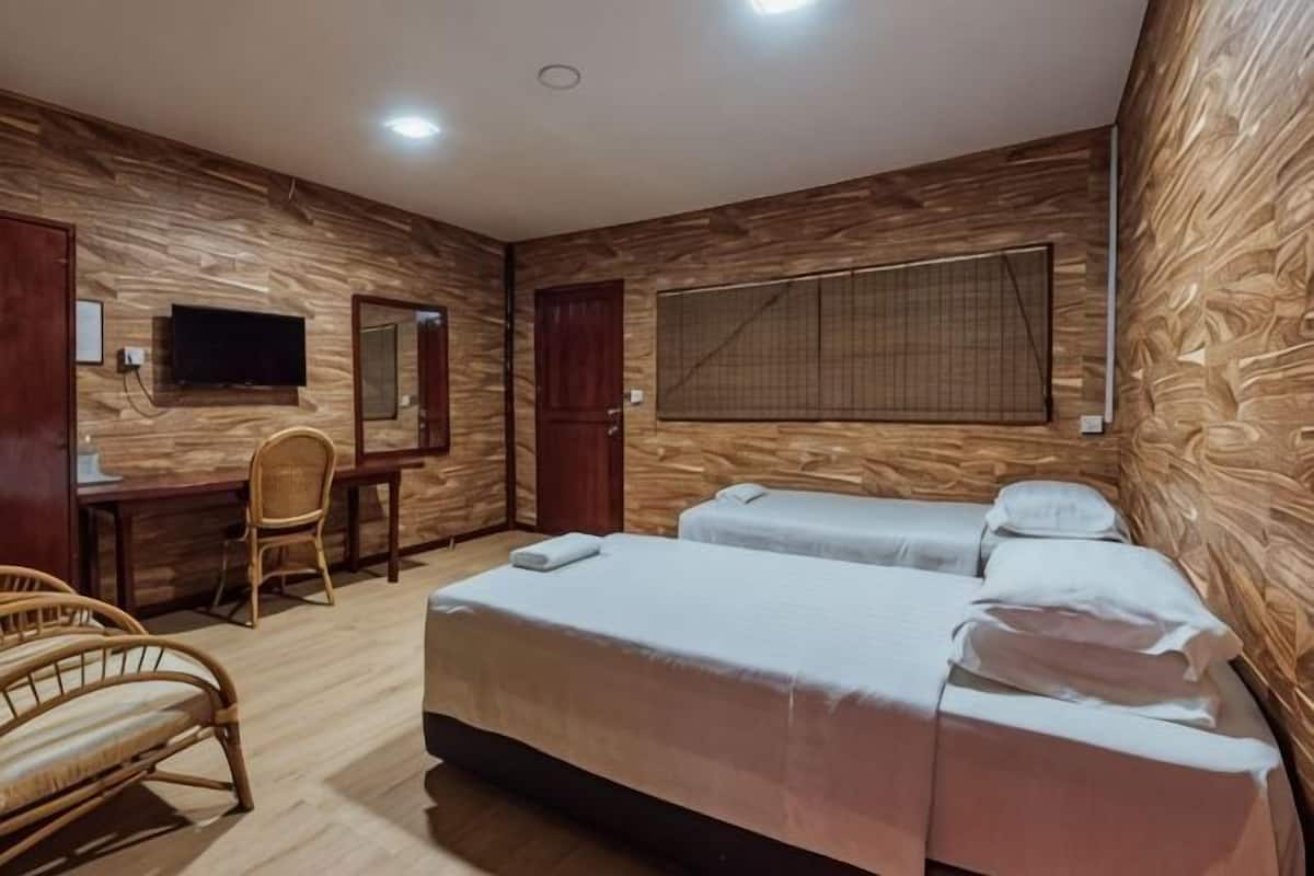 A room with two beds, a desk, a chair, a TV, and a window with blinds.