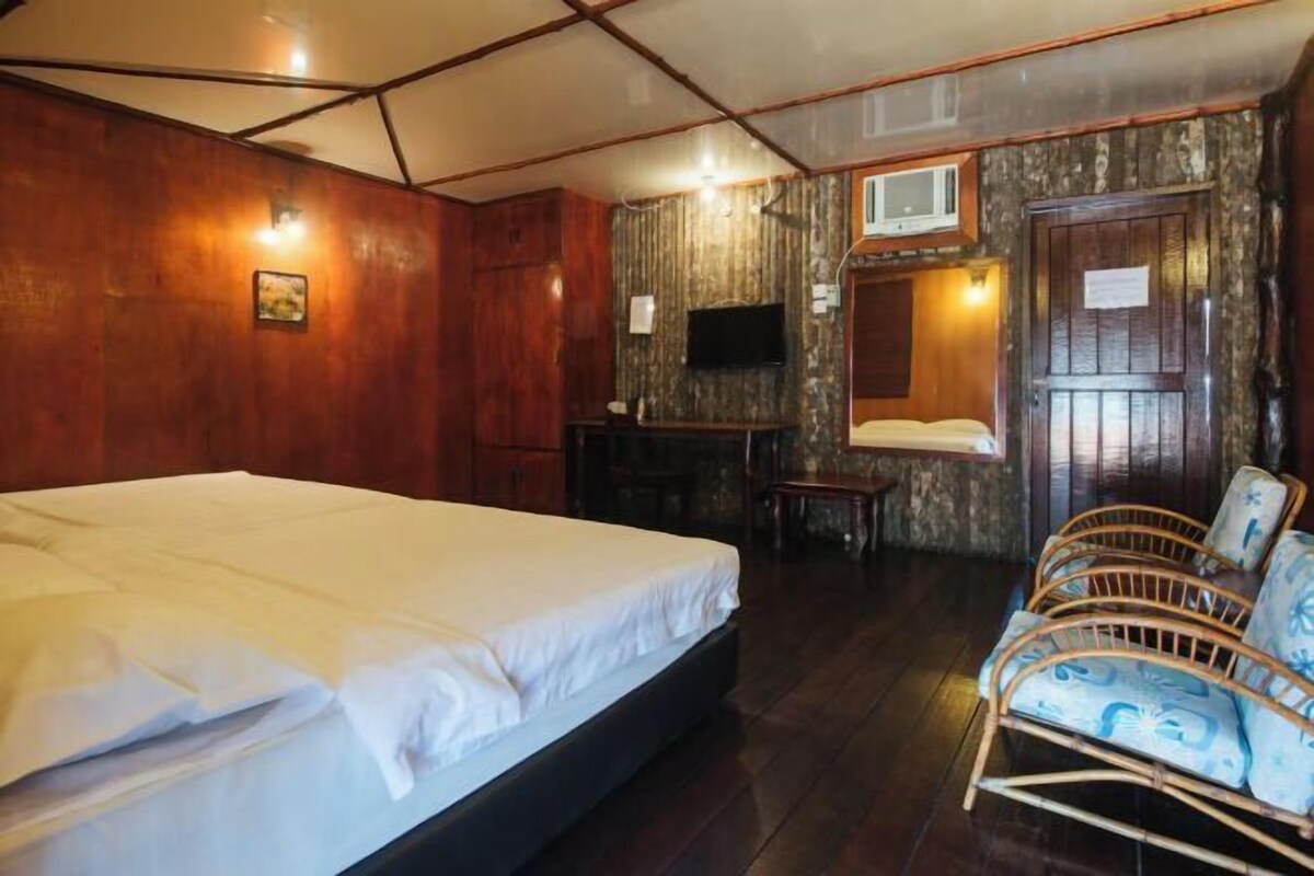 A room with a bed, a television, a desk, and a chair.