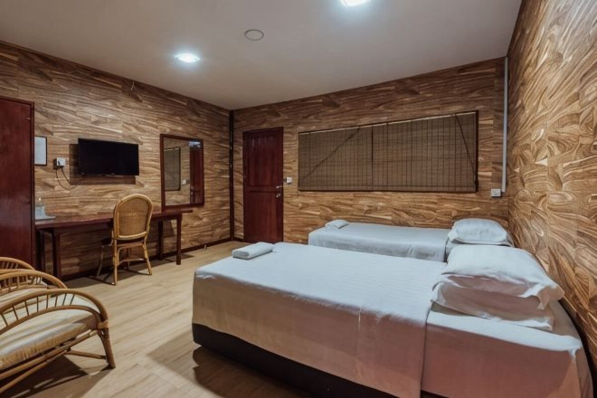 Una habitación con dos camas, un escritorio, una silla, un televisor y una ventana con persianas.
