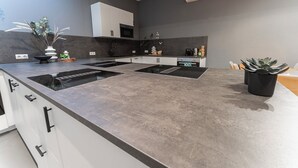 Une cuisine moderne dotée d’un îlot central, d’un four encastré et de meubles de rangement blancs.