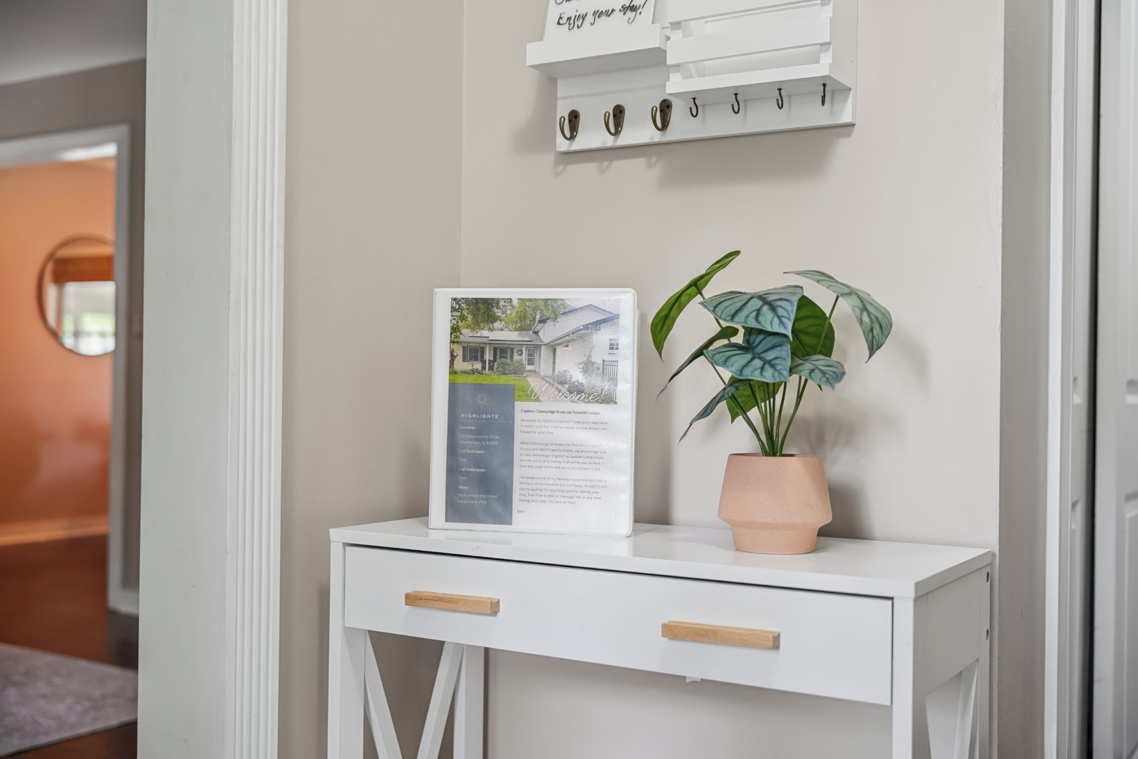 A white desk with a welcome sign and a potted plant.