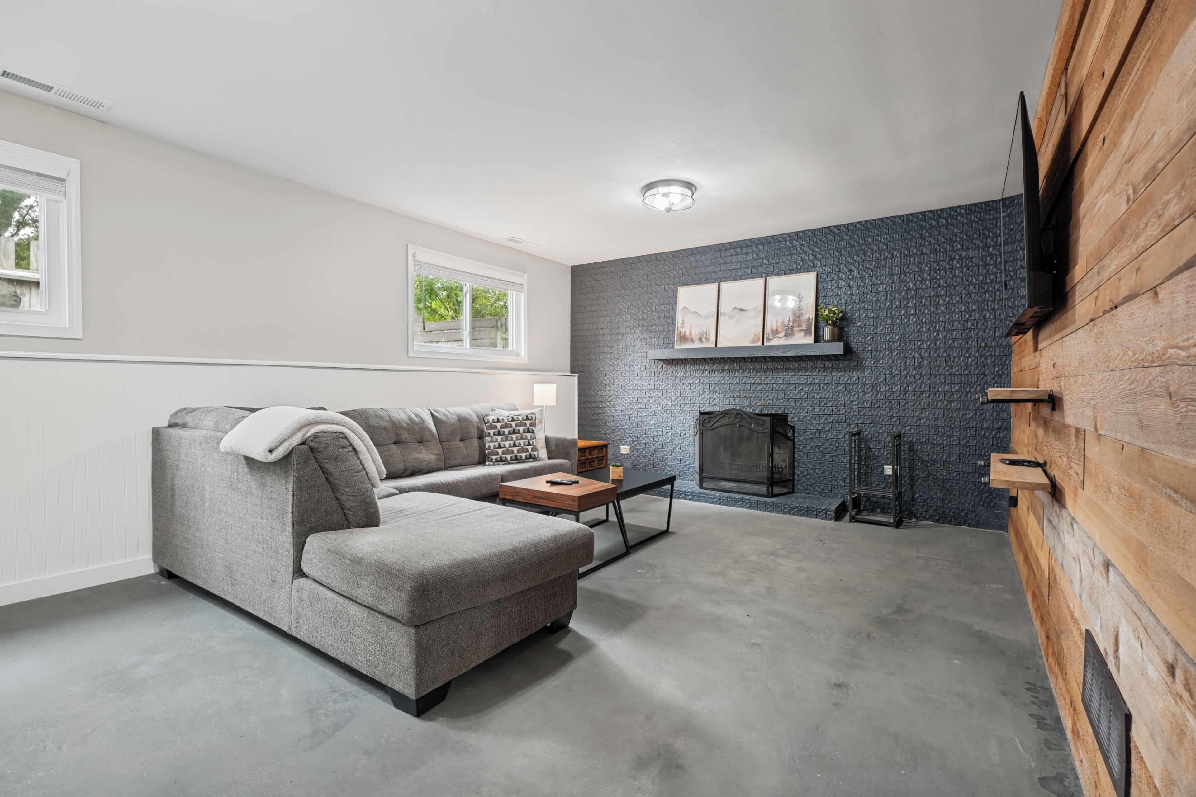 Un salon moderne avec un canapé d’angle gris, une table basse et une cheminée.