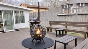 A deck with a fire pit, benches, and a wooden fence.