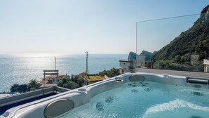 A hot tub with a view of the sea and a mountainous landscape.