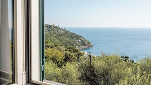 A coastal view from a window overlooking a hillside with a clear sky.
