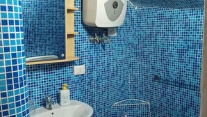 Une salle de bain avec des carreaux de mosaïque bleus, un lavabo blanc, un miroir et un sèche-mains.