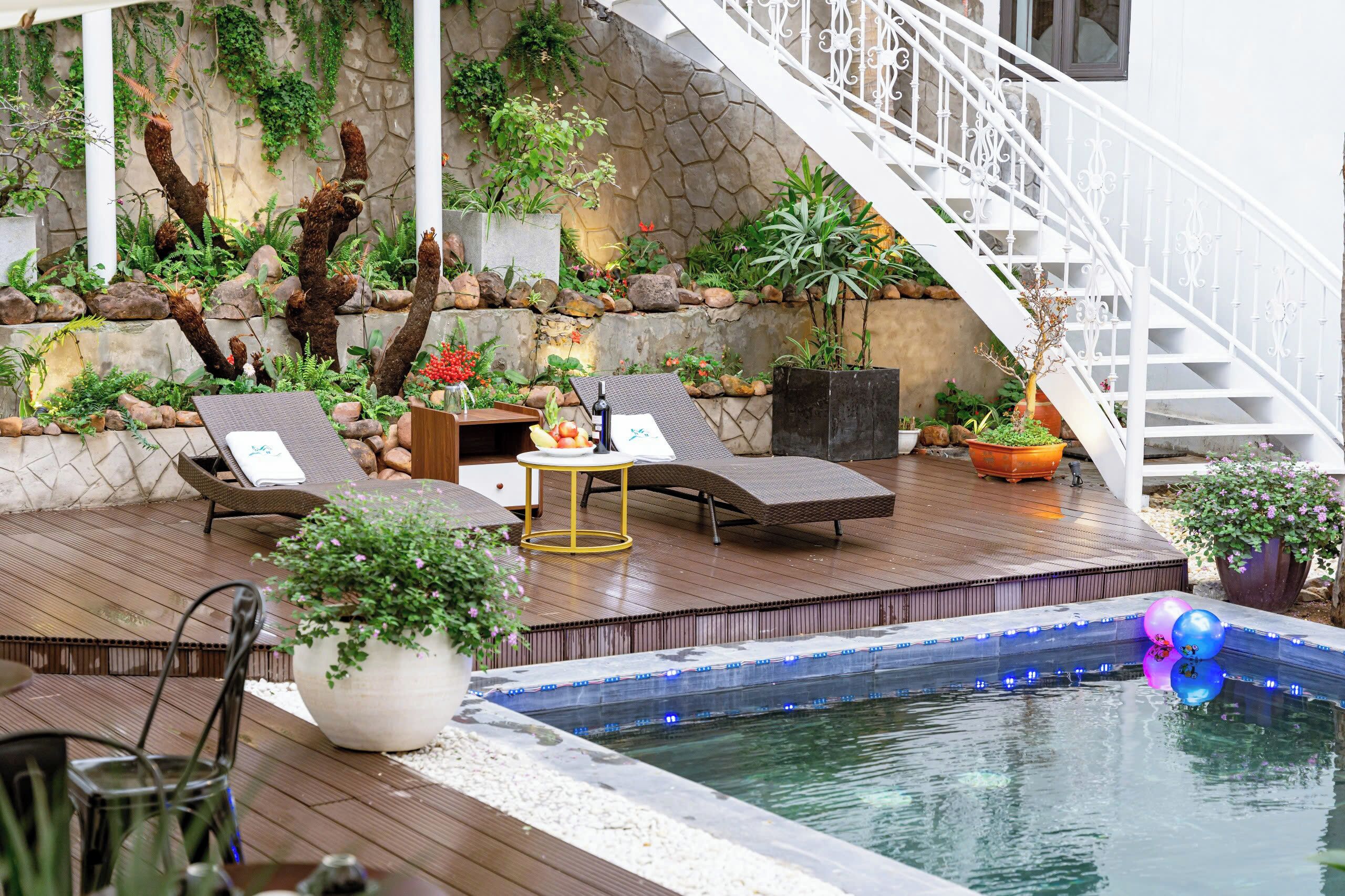 A poolside area with lounge chairs, a hot tub, and a staircase.