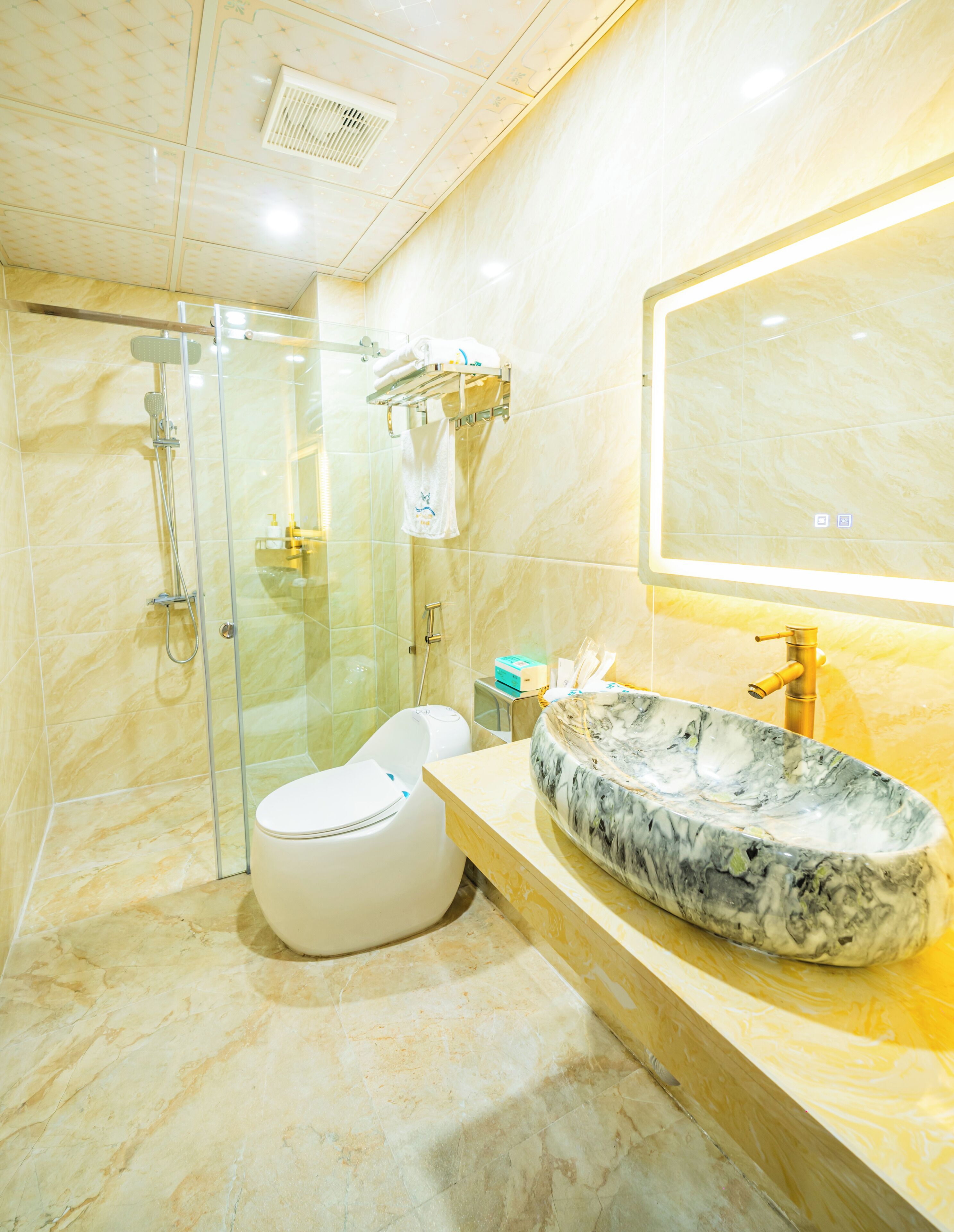 A modern bathroom with a marble sink, a glass-enclosed shower, and a toilet.