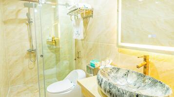 A modern bathroom with a marble sink, a glass-enclosed shower, and a toilet.
