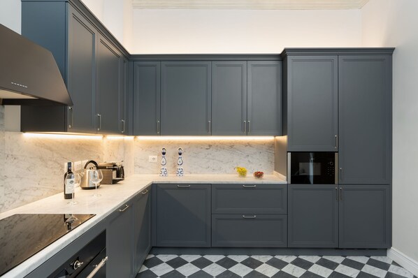 A modern kitchen with dark grey cabinets, a marble countertop, and a black and white checkered floor. - Palazzo Pazzi Vitali Luxury Apartments In Florence. (Florence)