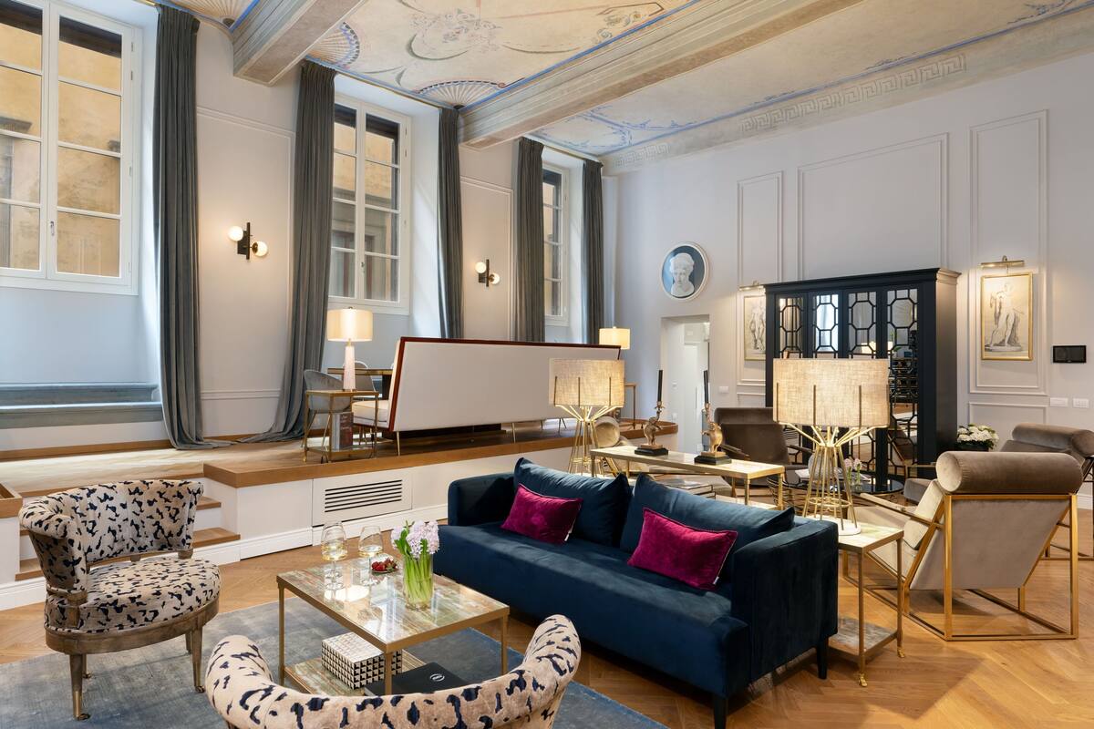 A spacious living room with a blue sofa, patterned armchairs, and a coffee table.