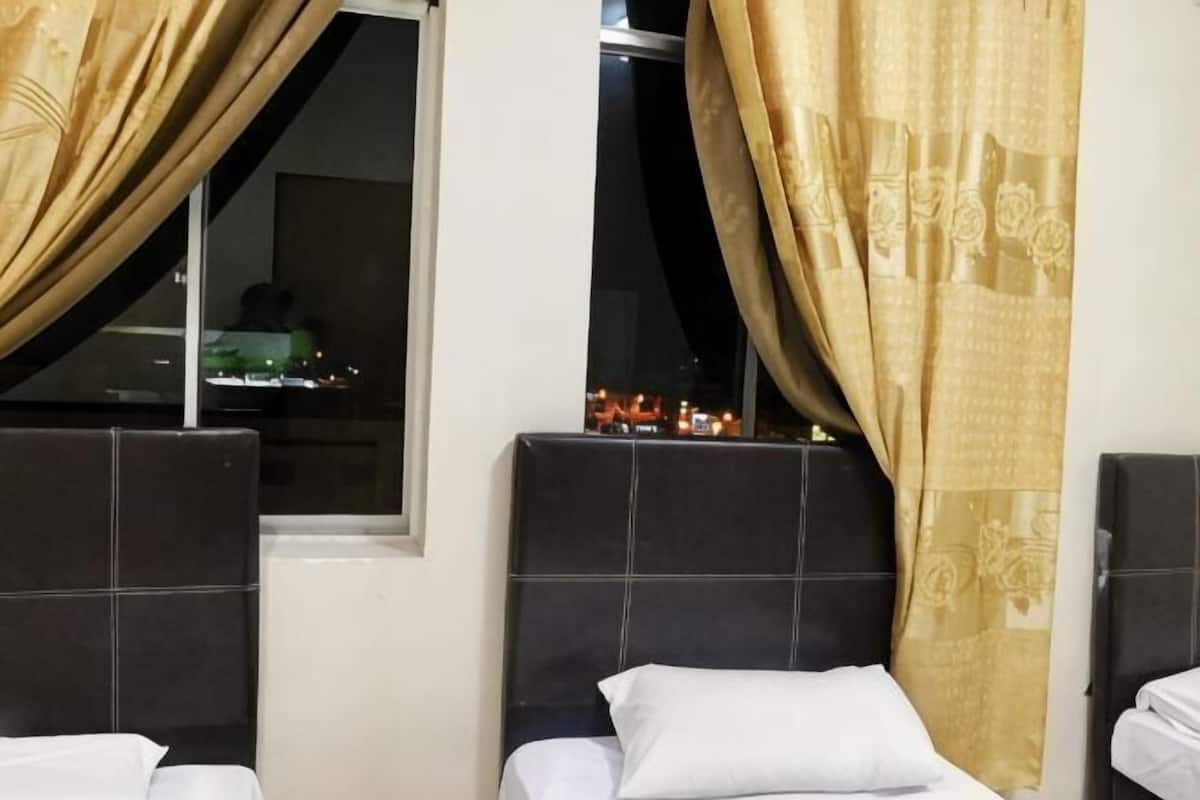 Habitación de hotel con dos camas, una ventana con cortinas y vista a la ciudad de noche.