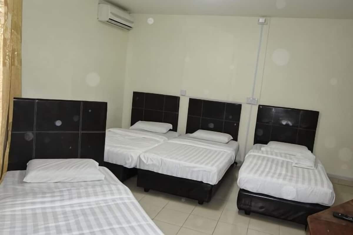 Una habitación de hotel con cuatro camas, un escritorio de madera y un equipo de aire acondicionado.