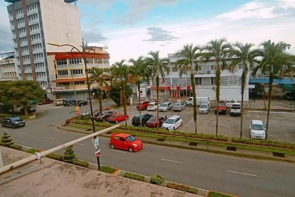 A street view with parked cars, palm trees, and buildings.