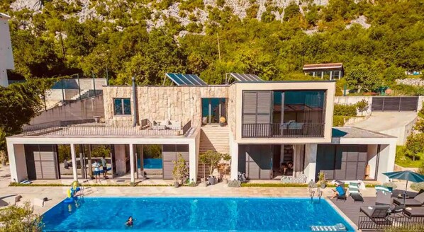 A modern two-story house with a swimming pool, outdoor seating, and solar panels. - Bayview and 17m pool villa (Kotor)
