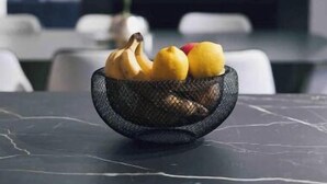 A kitchen counter with a basket containing bananas and lemons.