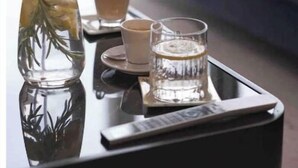 A tray with a glass of water, a glass of coffee, and a bottle with a cork.